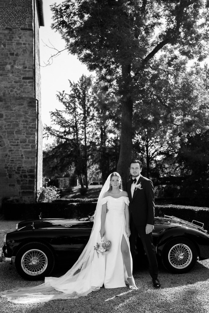 Getrouwd koppel poseert voor een oldtimer op hun trouwdag